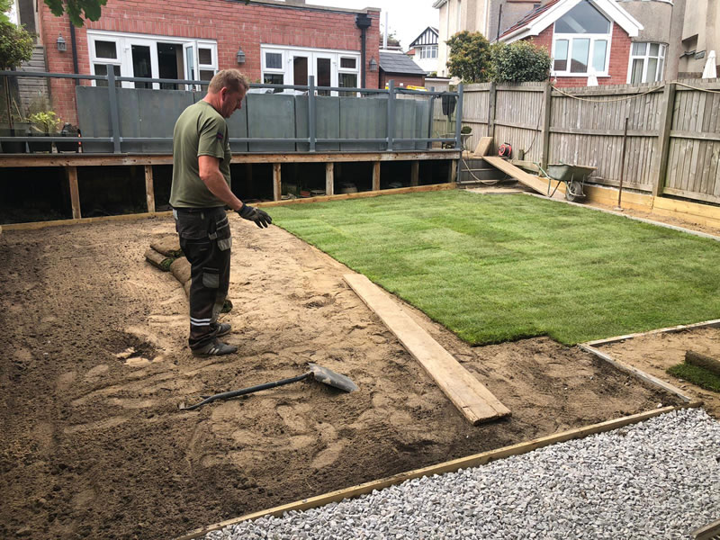 Sketty garden half turfed to the right person assesing work to left